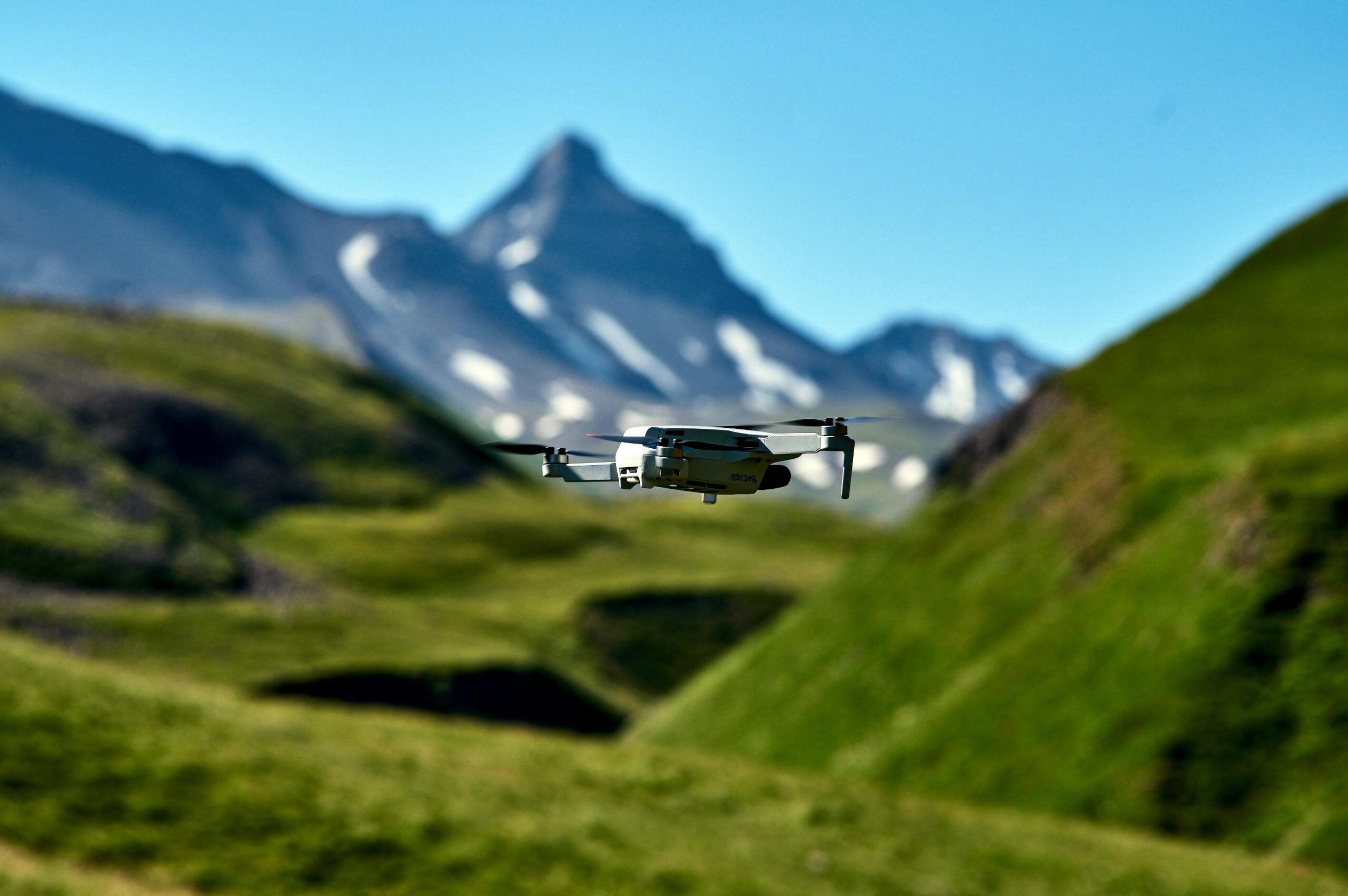 A drone flying over lush green hills with mountains in Dagestan, Russia.